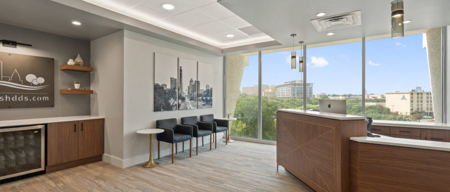 a modern dental office front desk with a large window and a bar.